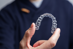 A person holding a clear plastic aligner