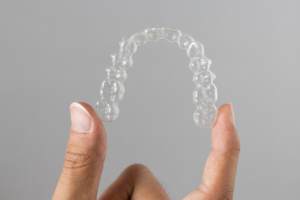 A hand holding a clear dental aligner