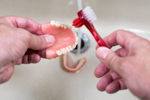 a person brushing dentures in a sink