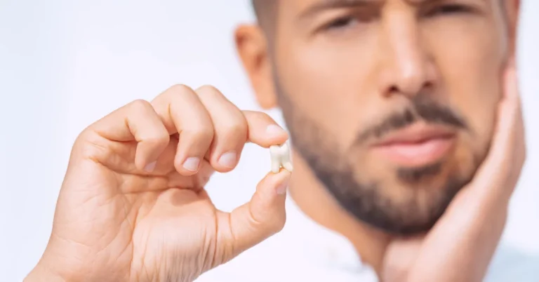 Wisdom Teeth in Naples - A man holding an extracted wisdom tooth while touching his jaw with a pained expression, indicating discomfort from wisdom teeth.
