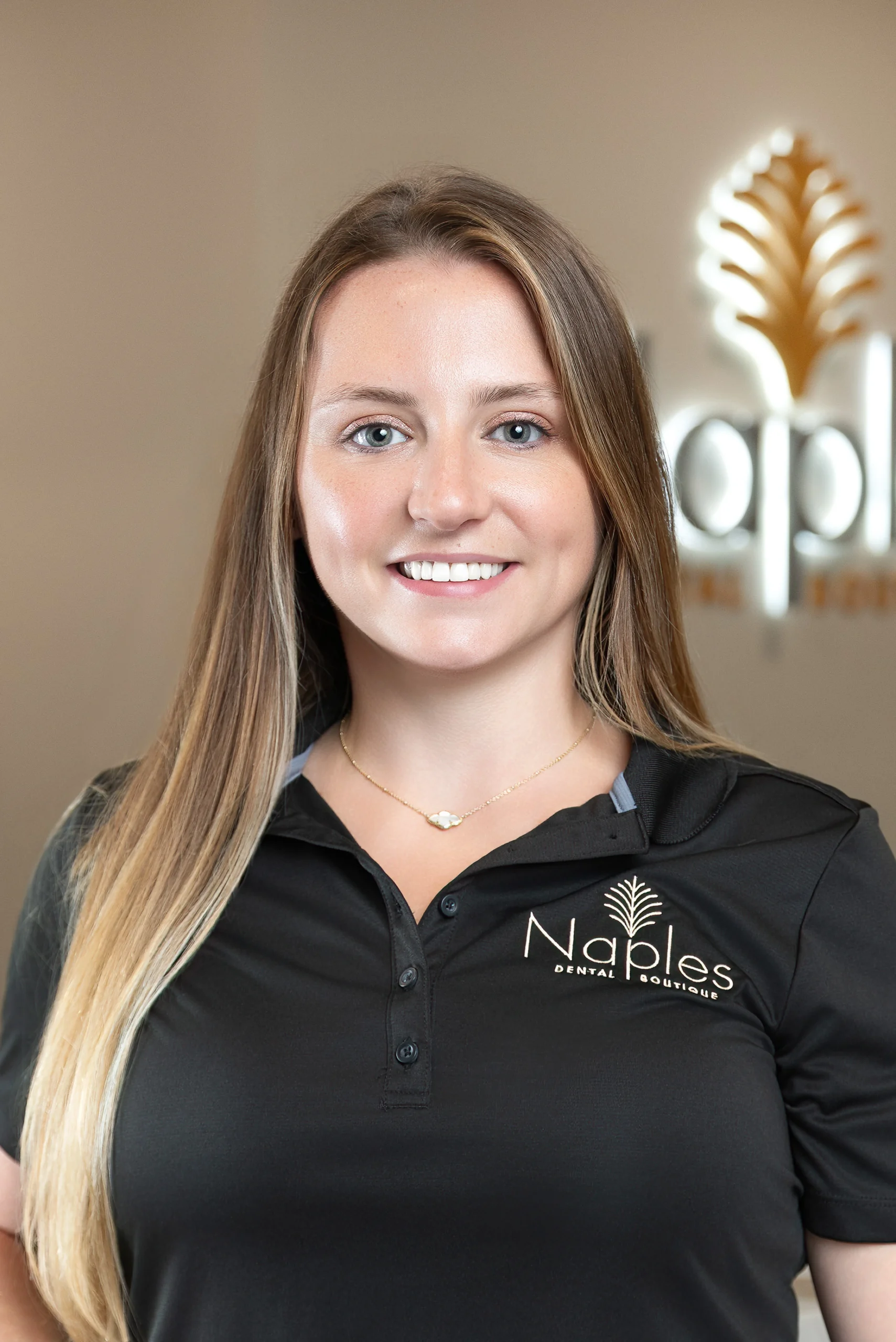 Robyn frey, team member at naples dental boutique, standing in the front reception area in naples, florida.